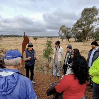 Australian Trustbuilding dialogue session White male speaking to semi-circle of white and indigenous Australians outdoors